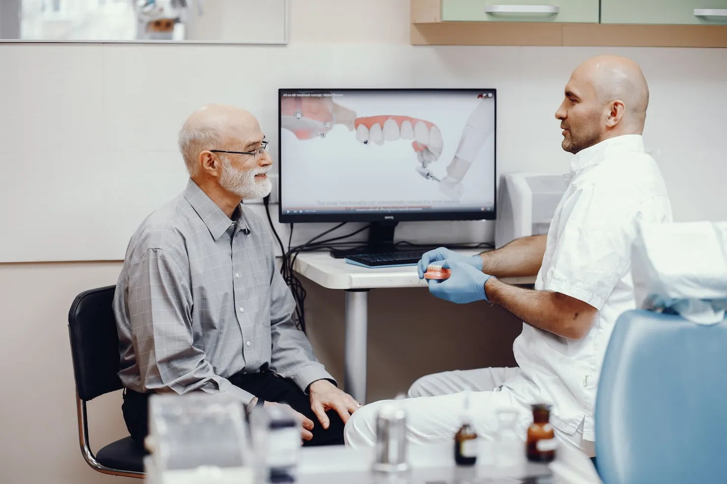 Dentist explaining All-on-4 dental implants cost and treatment procedure to an older patient in a Sydney clinic.